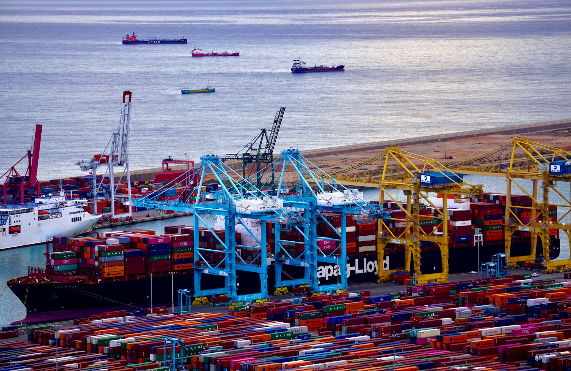 Loading of maritime containers aboard vessels in a seaport. Photo @ Unsplash