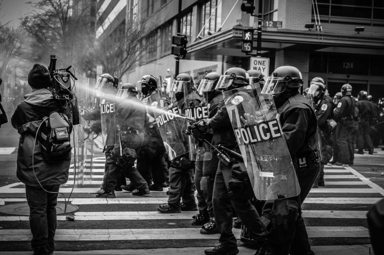 Riot police at a protest. Photo by Spenser H @ Unsplash