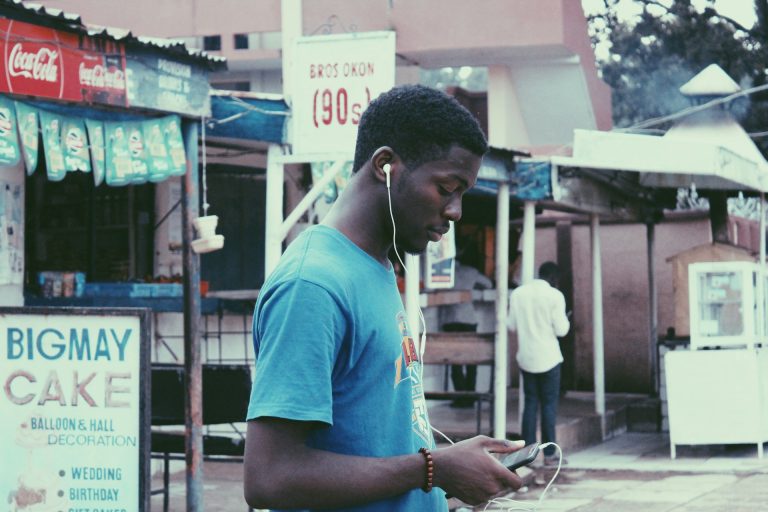 A Nigerian teenager with his phone. Photo by Muhammad-Taha Ibrahim @ Unsplash