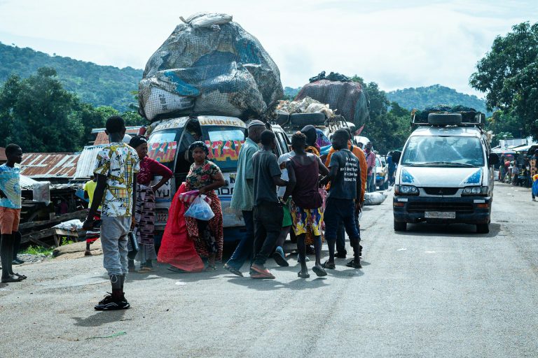 Passengers and hawkers at a street transport scene. Photo by Ümit Yıldırım @ Unsplash