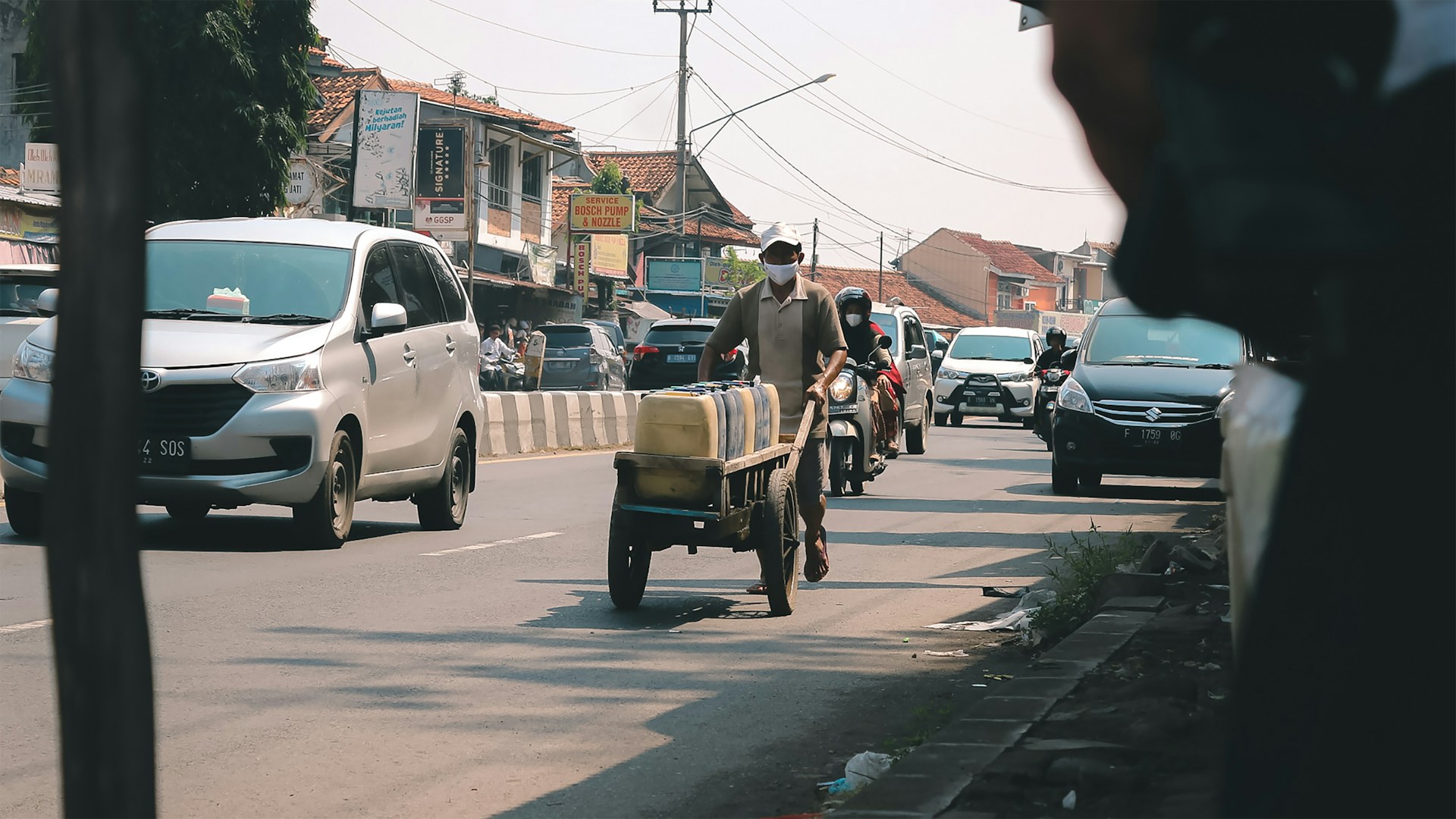 Man pushing truck with gallons of water in Benin. Photo by Dananjaya Nugraha @ Unsplash