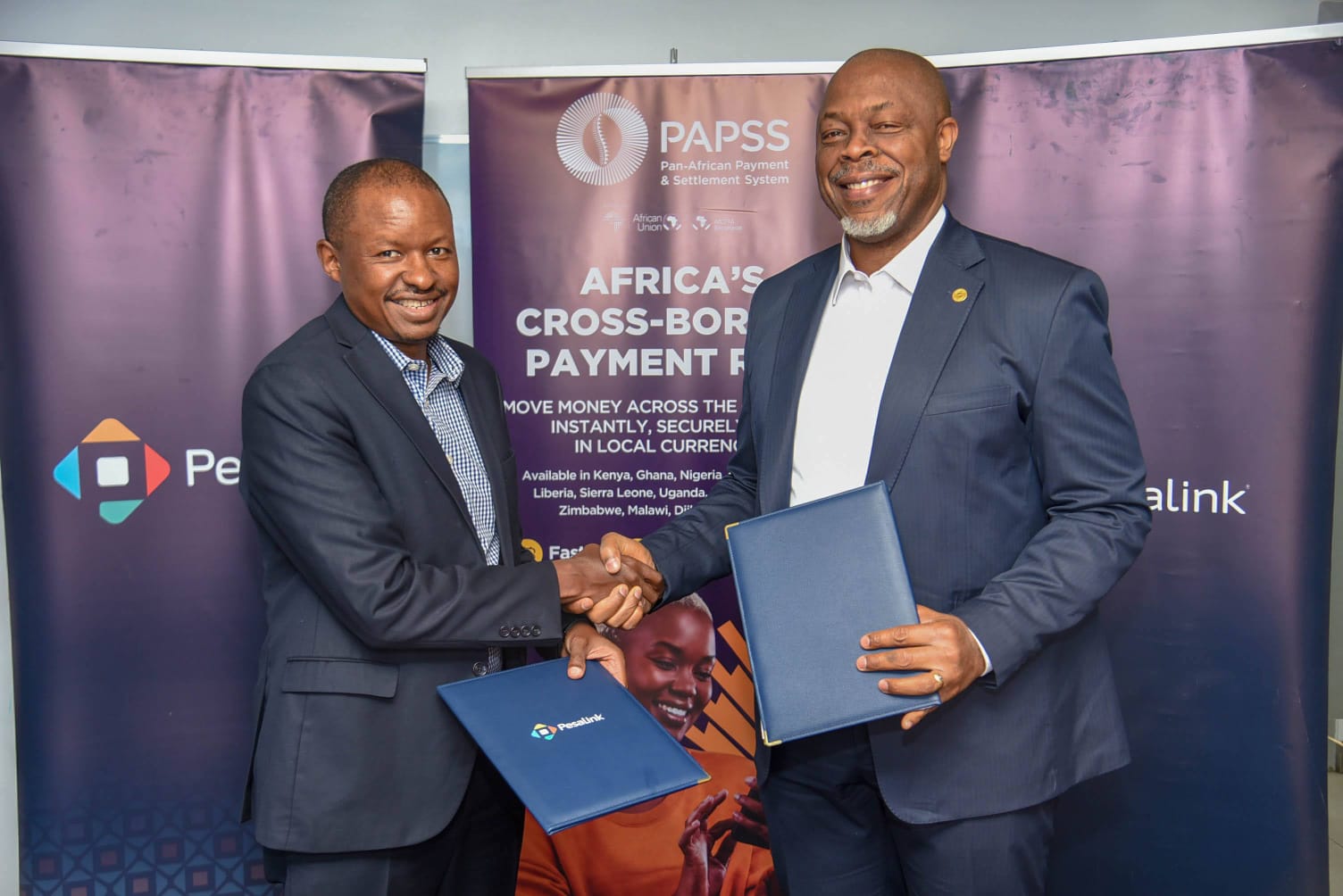 Pesalink CEO, Gituku Kirika (left) and PAPSS CEO, Mike Ogbalu III (right) exchange the partnership documents following the signing of the agreement in Nairobi, Kenya.