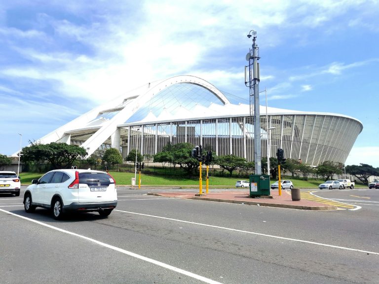 Vehicle driving pass the Iconic Moses Mabhida Stadium. Photo by Thokozani Nkala @ Unsplash