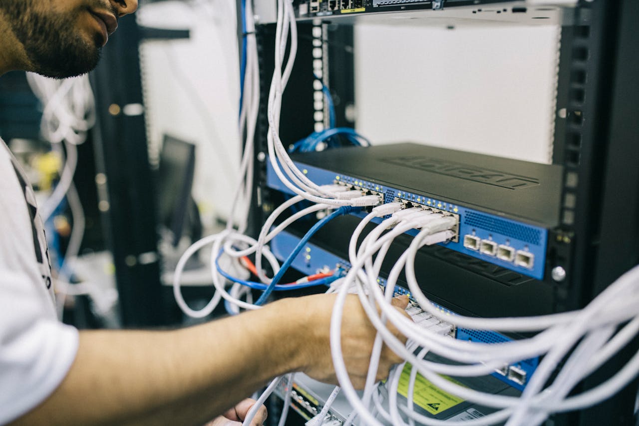 Electronics engineer fixing cables at a Data Centre. Photo @ Pexels