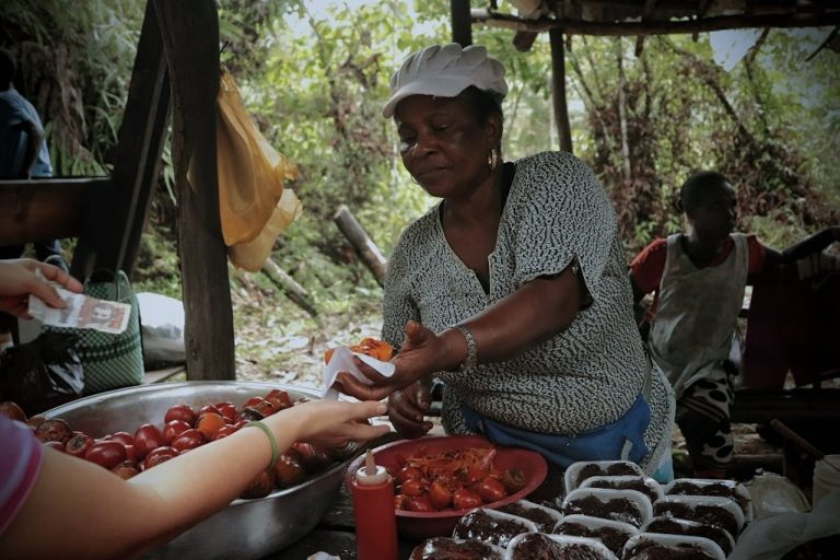 An outdoor street vendor sells fresh produce and food in a rustic setting in Mozambique. Photo by Natalia De la Pava @Pexels