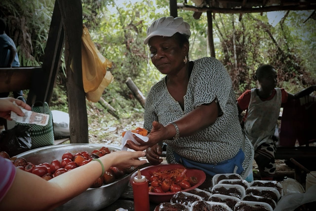 An outdoor street vendor sells fresh produce and food in a rustic setting in Mozambique. Photo by Natalia De la Pava @Pexels