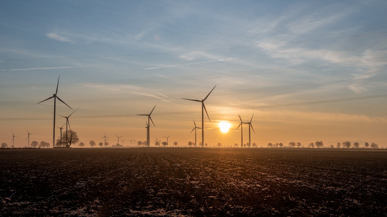 A scenic view of wind turbines at sunrise, capturing sustainable energy. Photo by Lorna Pauli @Pexel