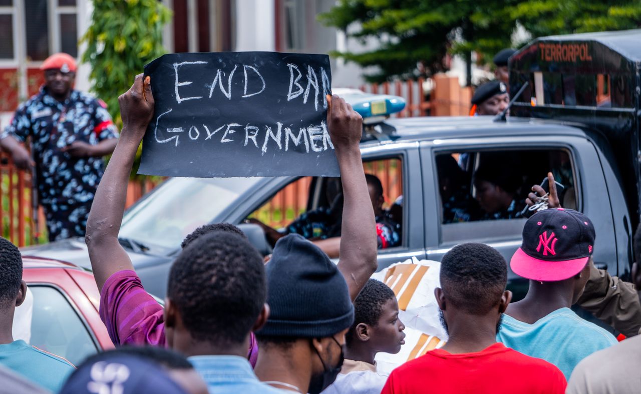 Police watch on as protesters hold a sign demanding change in Nigeria during a peaceful demonstration. Photo by Dokun Ayano @Pexels