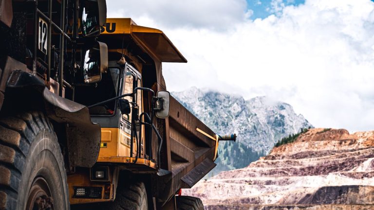 Large mining truck in a scenic mountain setting on a clear day. Photo by Usame Dzinovic @ Pexels