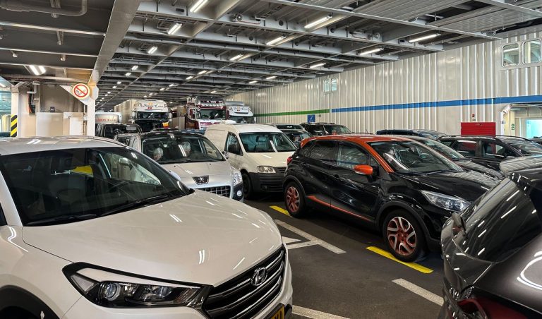 Cars and trucks parked closely together on a ferry deck. Photo by Freek Wolsink @ Pexels
