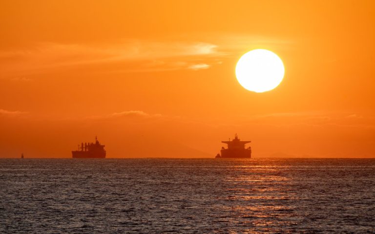 Oil tankers silhouetted against a vibrant sunset over the Pacific Ocean. Photo by Soly Moses @Pexels