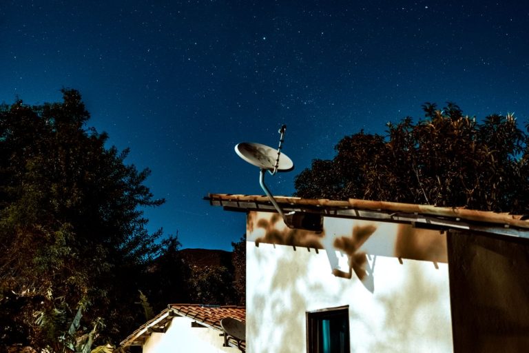 A serene starry night sky over a rural house with a satellite dish. Photo by Lucas Andrade @ Pexels
