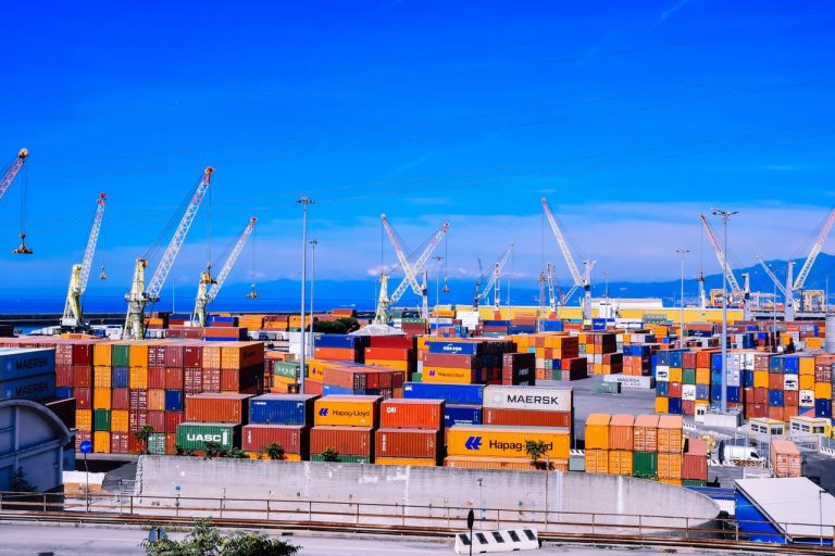 A bustling shipping port with colorful stacked containers. Photo by Andrea Musto @ Pexels