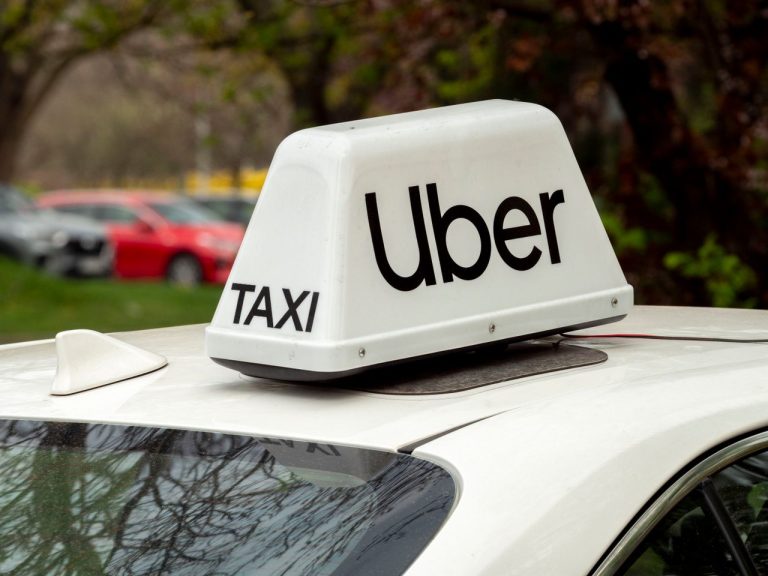 Close-up of a white Uber taxi sign on a car roof