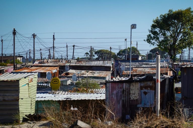 An informal settlement with numerous makeshift rooftops and power lines. Photo by Magda Ehlers @ Pexels