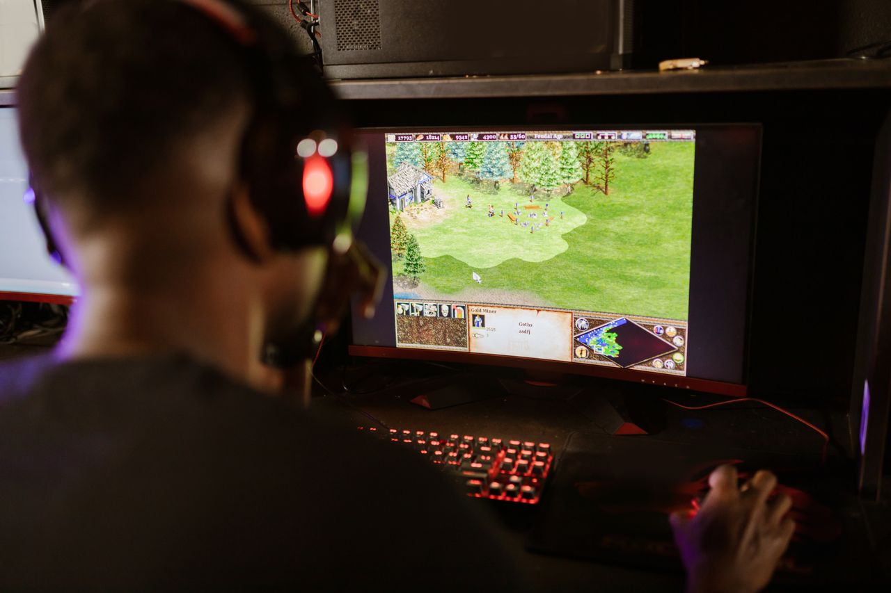 A gamer intensely playing a strategy game on a high-resolution monitor indoors. Photo by RDNE Stock @ Pexels